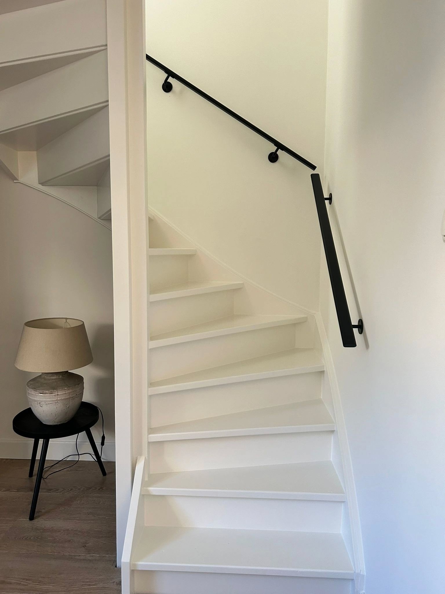 Detail van zwarte rechthoekige trapleuning gemonteerd aan muur